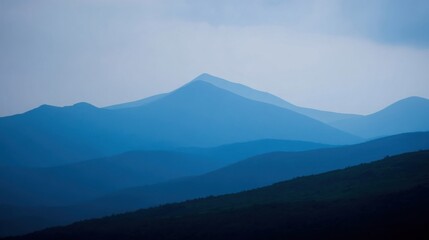 Mountain landscape with atmospheric perspective, layers of blue shades, darker tones in foreground,