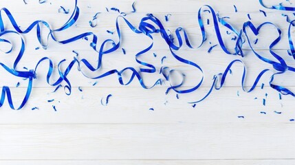 Bright blue streamers twisted and looped on a light wooden surface create a festive celebration look with scattered smal