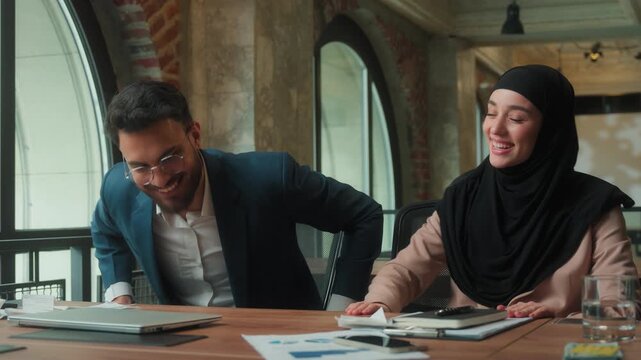 Carefree business team finish work leaving office Hindu businessman Arabian businesswoman in hijab two colleagues partners success satisfied accomplish laptop work paperwork job done going away happy