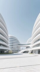 Modern white architectural complex with curved buildings and open plaza under clear sky