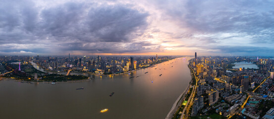 Wuhan city view with the Yangtze River flowing through its urban landscape, lights illuminate the city during the evening hours, boats travel on the water.