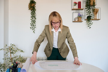 Woman architect analyzing blueprint for building design