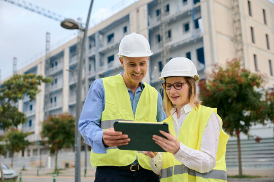 Engineers collaborating on construction site using digital tablet - Powered by Adobe