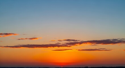 Fototapeta premium Vibrant sunset sky with clouds and orange hues over horizon.