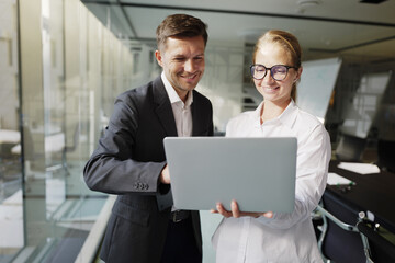 Colleagues collaborating on a laptop in a modern office environment