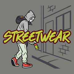 A hooded figure sprays the word streetwear on a brick wall in a back alley