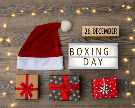 Overhead shot of boxing day gifts with santa hat and lights on rustic wood