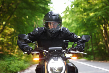 Young man in helmet driving modern motorcycle outdoors