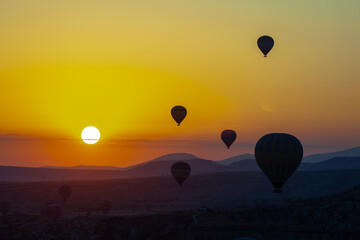 Hot air balloon flying over rocky landscape at sunrise in Cappadocia. Turkey