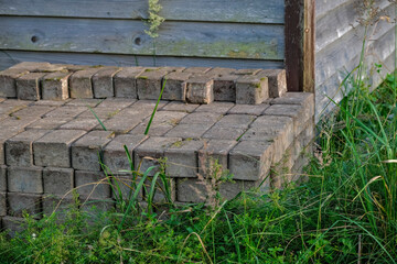 pile of used paving stones near wooden wall