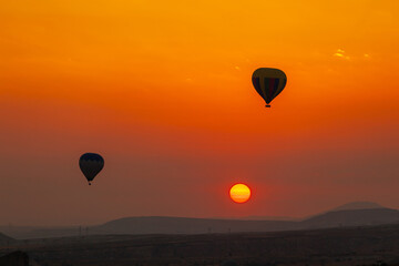 Hot air balloon flying over rocky landscape at sunrise in Cappadocia. Turkey