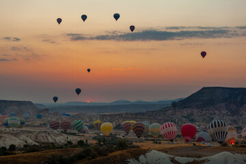 Hot air balloon flying over rocky landscape at sunrise in Cappadocia. Turkey