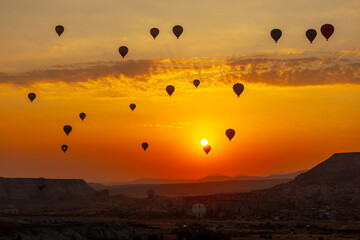 Hot air balloon flying over rocky landscape at sunrise in Cappadocia. Turkey