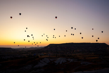 Hot air balloon flying over rocky landscape at sunrise in Cappadocia. Turkey