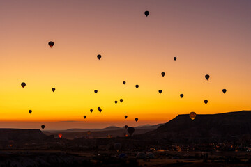 Hot air balloon flying over rocky landscape at sunrise in Cappadocia. Turkey