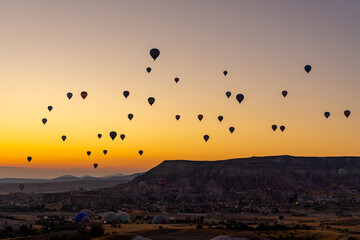 Hot air balloon flying over rocky landscape at sunrise in Cappadocia. Turkey