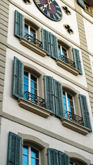 Fototapeta premium Close-up of a building with decorative shutters, iron balconies, and a clock. Concept of European architecture and stylish design.