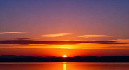 Obraz premium Beautiful sunset over the lake with sun reflecting on the water surface