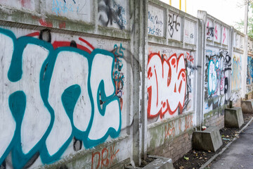 Colorful graffiti art on a concrete wall, showcasing vibrant designs and urban creativity, with a textured surface and surrounding greenery, reflecting street culture and artistic expression