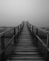 Obraz premium Foggy Wooden Pier Leading Into Mysterious Misty Landscape Scene