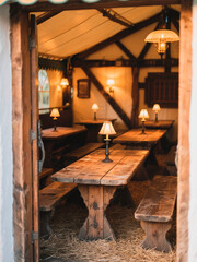 Rustic wooden interior of a cozy dining space featuring long tables and warm lighting, creating an inviting atmosphere for gatherings and meals with friends and family