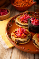 Panuchos, a typical dish from Yucatan, Mexico. A handmade, fried corn tortilla filled with beans, topped with cochinita pibil, pickled red onion, and habanero pepper.