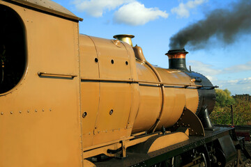 Old vintage locomotive steam railway train engine with smoke blowing from its chimney funnel, travel transport stock photo image