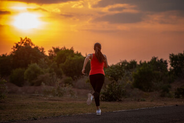 Young woman with a good figure jogging outdoors at sunset. Healthy lifestyle and sports concept.