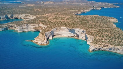 Naklejka premium Aerial view of a beach featuring white rocky cliffs surrounded by deep blue waters.