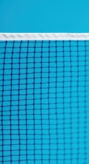A close-up view of a badminton net against a vibrant teal background, showcasing the intricate grid pattern and white border.