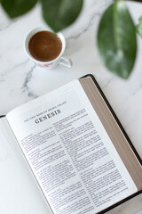 Genesis book in open holy bible with cup of coffee on white marble table. Top view. Christian study...