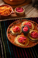 Panuchos, a typical dish from Yucatan, Mexico. A handmade, fried corn tortilla filled with beans, topped with cochinita pibil, pickled red onion, and habanero pepper.