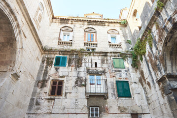 Obraz premium Different windows and green shutters on an old croatian building facade