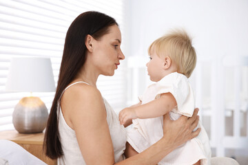 Mother and her cute little baby on bed in room