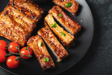 Hot grilled spare ribs from a summer BBQ served on a plate with sauce. Top view. Copy space