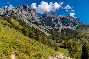 Obraz premium Alps mountains scenic landscape in summer. Austrian Alps scenery trekking path among the high mountain peaks in summer. Green mountain valleys with rocky peaks and lake in the Alps in Austria