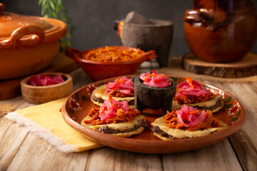 Panuchos, a typical dish from Yucatan, Mexico. A handmade, fried corn tortilla filled with beans, topped with cochinita pibil, pickled red onion, and habanero pepper.