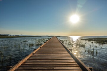 Obraz premium Wooden pathway along the coast at bright dawn in a scenic wetland