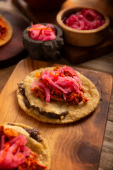 Panuchos, a typical dish from Yucatan, Mexico. A handmade, fried corn tortilla filled with beans, topped with cochinita pibil, pickled red onion, and habanero pepper.