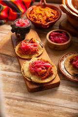 Panuchos, a typical dish from Yucatan, Mexico. A handmade, fried corn tortilla filled with beans, topped with cochinita pibil, pickled red onion, and habanero pepper.