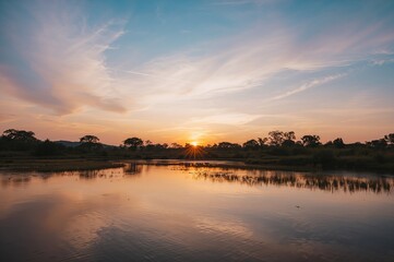 Obraz premium Soft pastel colors paint a serene sunset above fields and forests.