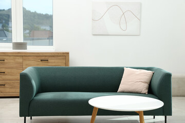 Comfortable sofa with pillow and side table indoors