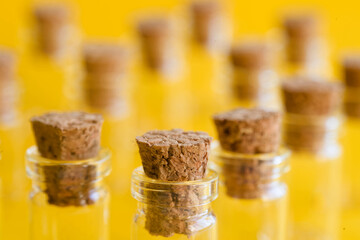 Macro view of many cork stoppers in mini glass bottles on a vivid yellow background; bright, colorful scene with focus on natural cork texture and detail. Photo
