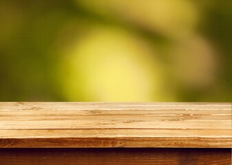 Empty wooden desk top with green tree background.