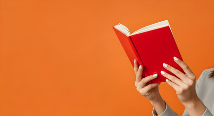 Woman enjoying a captivating novel with a vibrant red cover against a bold orange backdrop, perfect for book lovers and reading enthusiasts everywhere
