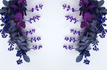 Flower frame made of purple leaves and berries on a white background