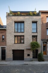 Naklejka premium Modern brick house with a green rooftop in an urban neighborhood during early morning light, showcasing contemporary architecture and an inviting facade