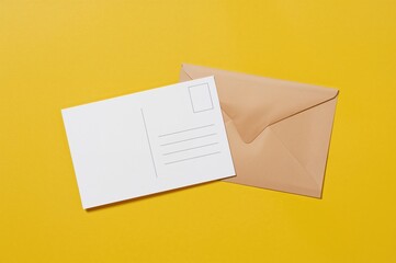 Two Empty Postcards Alongside a Big Brown Envelope on a Yellow Surface. Space for Text, Flat Lay, Design Mockup