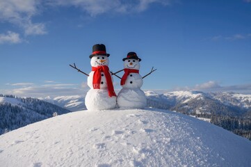 Obraz premium Two cheerful snowmen standing atop a snowy peak during winter