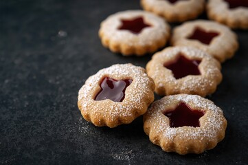Classic Linzer cookies with raspberry filling on a dark surface. Festive biscuits with jam inside. Focused image with empty space. Seasonal theme
